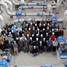 Overview of NAC group standing in front of large pipes