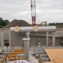 Process piping being craned into reservoir foundation